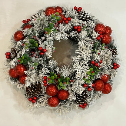 Realizzata con 135 rametti di pino artificiale innevato in pvc. Decorata con rametti artificiali di Bosso con bacche, pigne decorate, bacche in vetro di colore rosso e palline in plastica rosso glitter Diametro cm 60 circa. In negozio e online su tuttochic.live