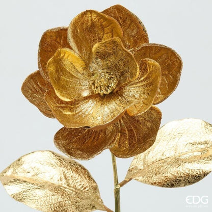 Inquadratura ravvicinata del bocciolo di magnolia EDG che mette in evidenza la texture tramata dei petali oro lucido e i dettagli metallizzati del pistillo.
