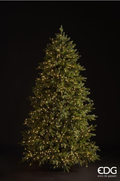 Albero di Natale artificiale Pino Cristallo EDG Enzo De Gasperi H 180 cm con 1500 mini LED a luce calda integrati e telecomando, posizionato in un salotto moderno accanto a una poltrona e un camino.