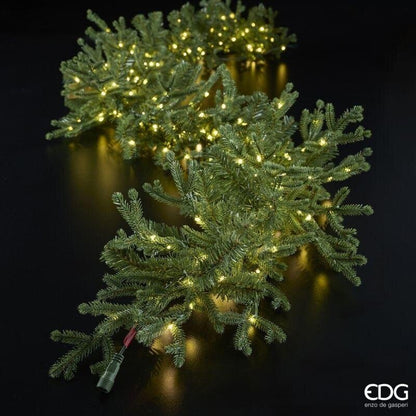 Festone di Natale in pino artificiale pre-illuminato EDG steso su piano nero con focus sullo spinotto per il collegamento elettrico in serie di più festoni.