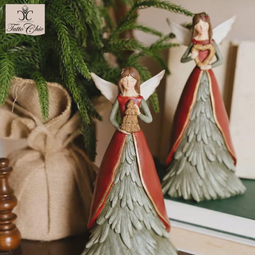 Statuina natalizia dell'angelo custode Magic Noel di Nuvole di Stoffa in resina, con grandi ali dorate intagliate, abito verde a forma di albero d'abete innevato e un cuore oro tra le mani, Tutto Chic.