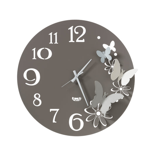Orologio da parete in metallo di colore fango con fiori e farfalle di colore alluminio, avorio e bianco, quadrante con numeri arabi e dallo stile minimale. E' abbellito da quattro farfalline che svolazzano fra i petali di fiori intagliati nel ferro. Dimensione: diametro 45 cm. In negozio e online su tuttochic.live