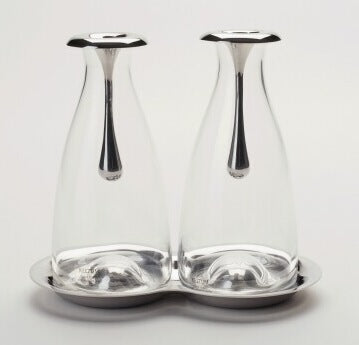Set olio e aceto in vetro soffiato e acciaio inox dal design particolare. Disegnato da Gijs Bakker gioielliere e designer industriale olandese. I design di Bakker coprono gioielli, accessori per la casa ed elettrodomestici, mobili, interni... Dimensioni: 18 x 10,5 x 16. In negozio e online su tuttochic.live
