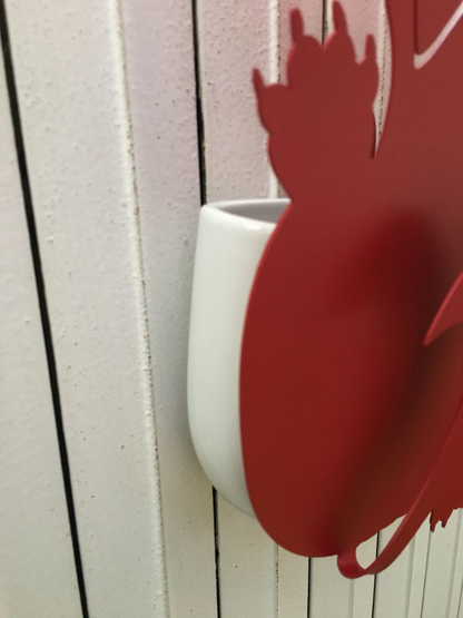 Umidificatore in metallo di colore rosso. Corredato di un contenitore in porcellana per l'acqua e il gancio in metallo per appenderlo a qualunque radiatore. Dimensioni: 22 x 5 x h 40 cm