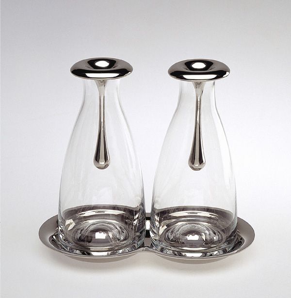 Set olio e aceto in vetro soffiato e acciaio inox dal design particolare. Disegnato da Gijs Bakker gioielliere e designer industriale olandese. I design di Bakker coprono gioielli, accessori per la casa ed elettrodomestici, mobili, interni... Dimensioni: 18 x 10,5 x 16. In negozio e online su tuttochic.live