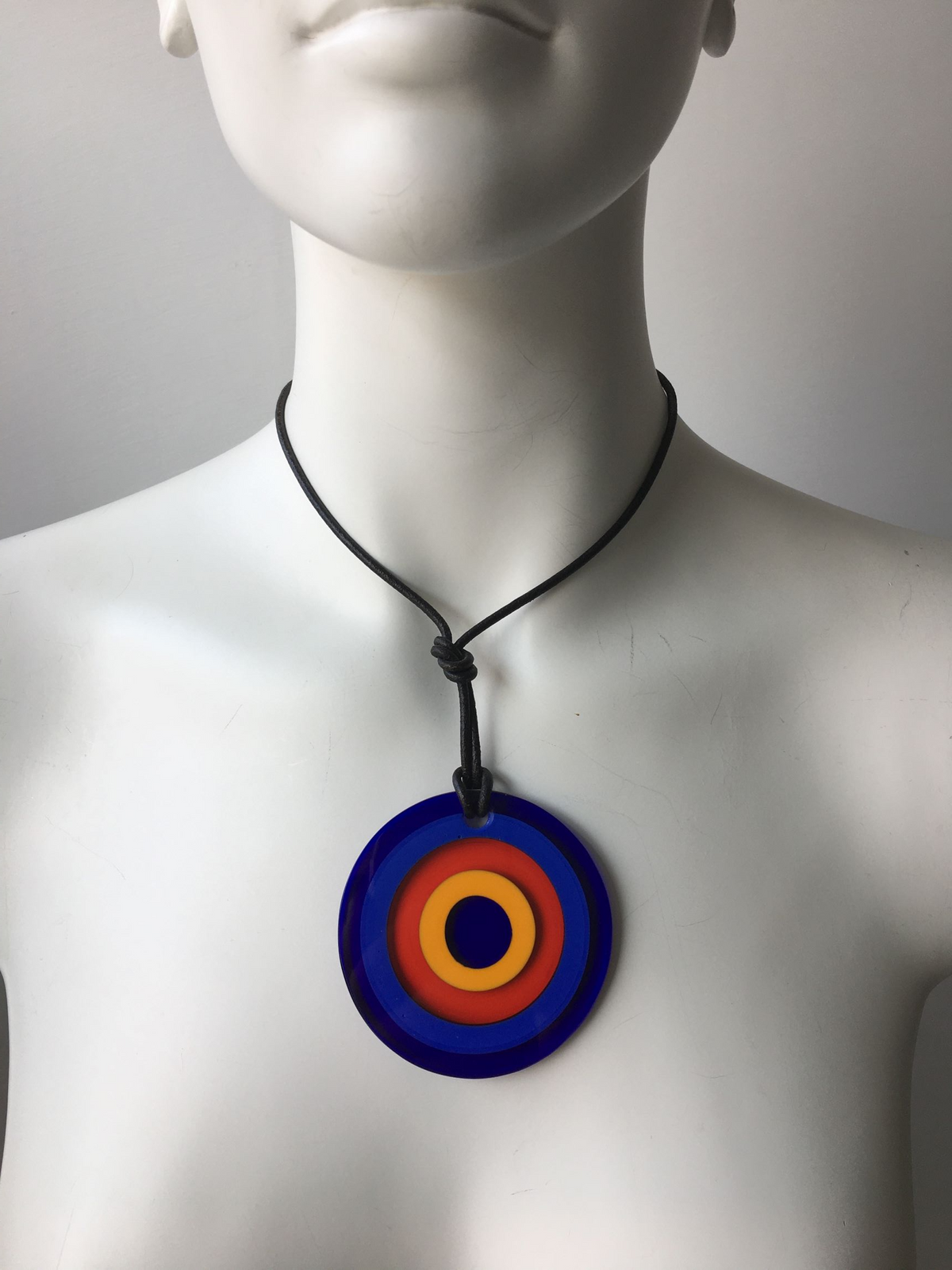Pendente in cristallo di Murano rifinito a mano con motivi decorativi applicati a caldo: murrina ad anelli. Dotato di laccetto in cuoio. Dimensioni: diametro cm 6,5