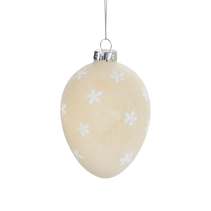 Uovo da appendere in vetro satinato di colore beige decorato con fiorellini bianchi. Dimensioni: Ø 7 x 10,5. In negozio e online su tuttochic.live