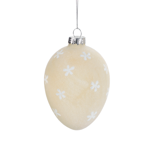 Uovo da appendere in vetro satinato di colore beige decorato con fiorellini bianchi. Dimensioni: Ø 7 x 10,5. In negozio e online su tuttochic.live
