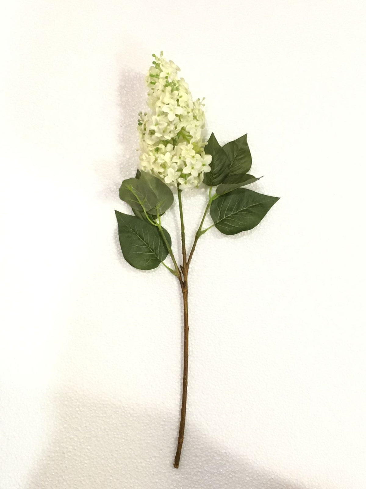 Fiore artificiale Lillà Eden di colore bianco. Dimensioni: cm 52. Petali e foglie in tessuto, rametti in plastica. In negozio e online su tuttochic.live