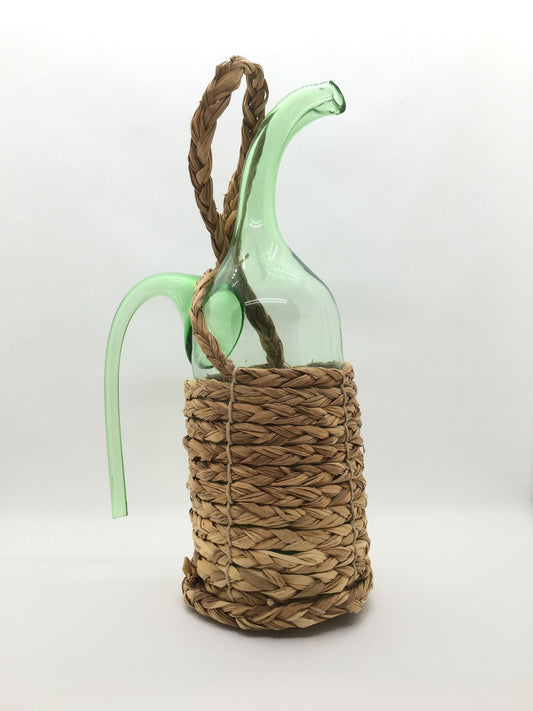Bottiglia decorativa aspiraliquidi in vetro ricoperta con paglia intrecciata naturale. Dimensioni: cm 16 x 25 h. In negozio e online su tuttochic.live