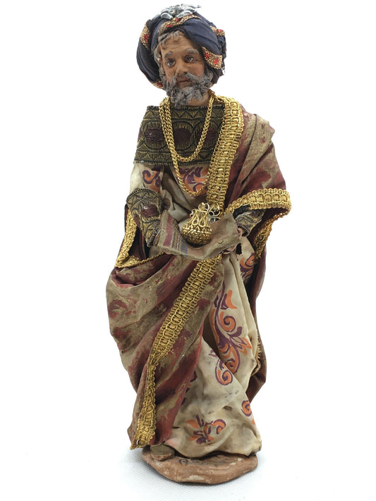 Statuina del Re Magio Gaspare per presepe di Angela Tripi, alta 20 cm, in terracotta e stoffa con mantello rosso e oro, turbante gioiello e cofanetto dorato tra le mani.
