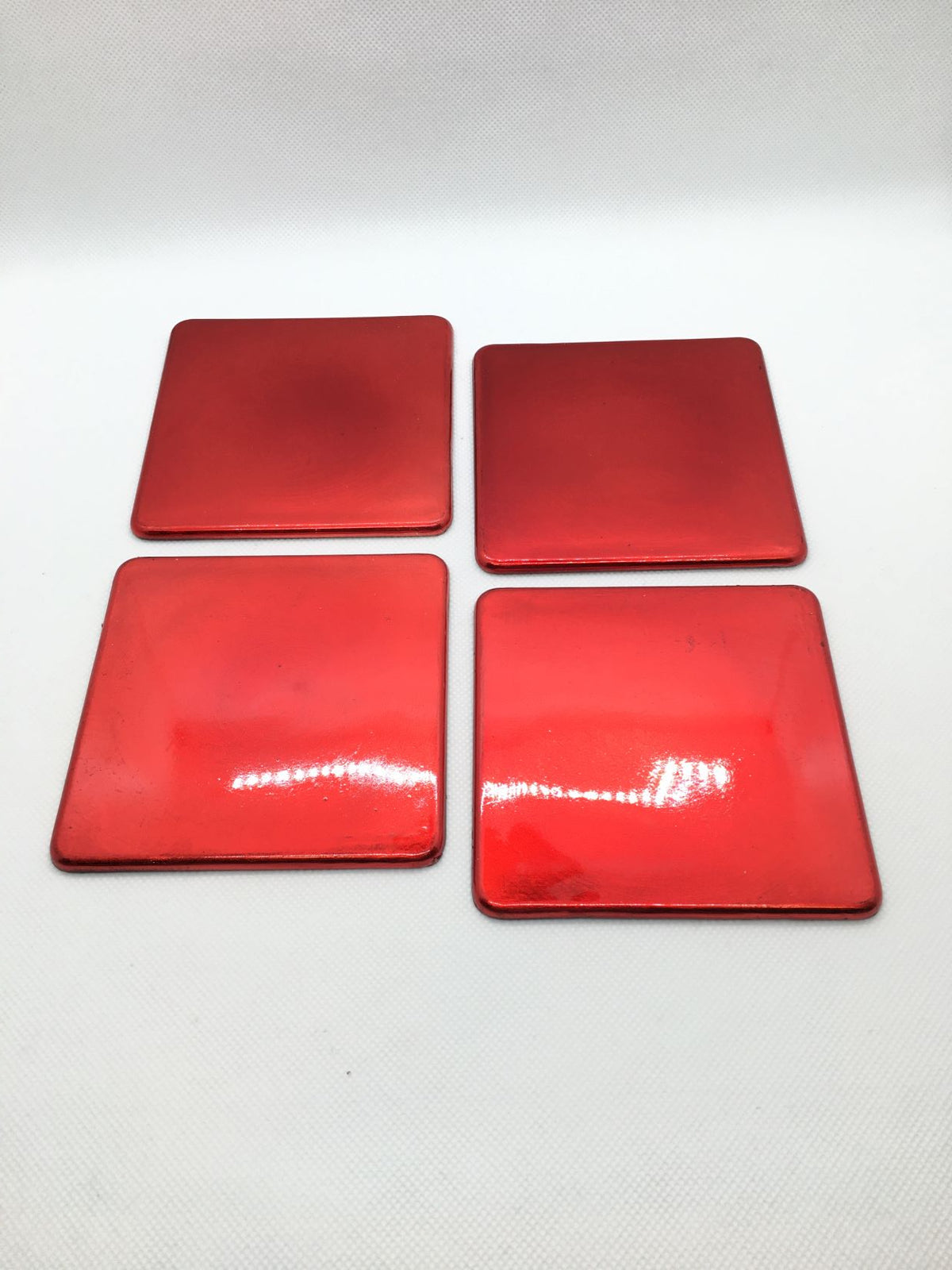 Set di 4 sottobicchieri in plastica effetto metallo di colore rosso. Dimensioni: sottobicchiere singolo cm 10 x 10. In negozio e online su tuttochic.live