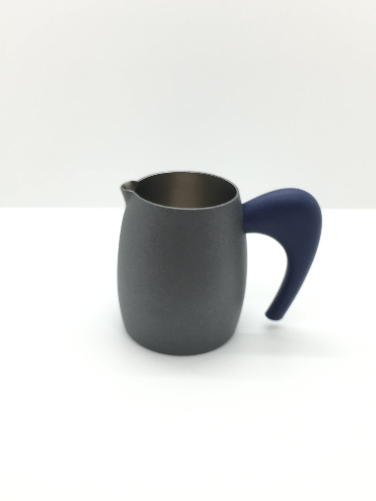 Lattiera in acciaio inox lucido all'interno e brunito all'esterno con manico in plastica di colore blu scuro. Dimensioni: cm 9 (con manico) x 6 x 7 h. In negozio e online su tuttochic.live