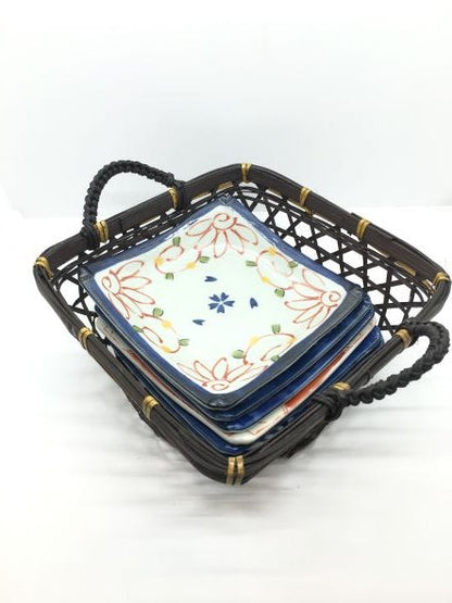 Set di 6 piattini in porcellana giapponese Saiegawari con cestino in vimini di colore nero. Dimensioni: piattino cm 14 x 14 - cestino cm 19, 5 x 25 (con manici) x 11,5 h (con manici). In negozio e online su tuttochic.live