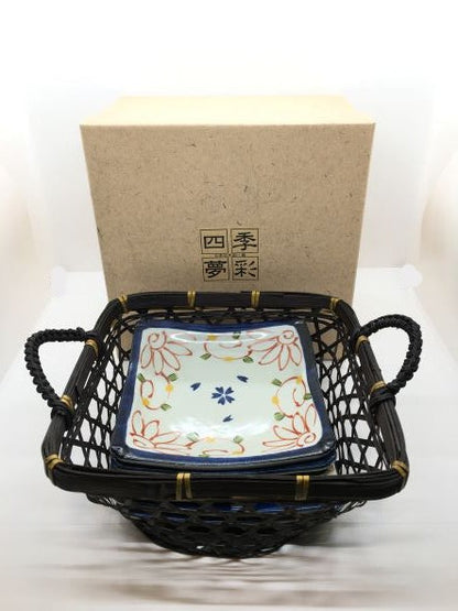 Set di 6 piattini in porcellana giapponese Saiegawari con cestino in vimini di colore nero. Dimensioni: piattino cm 14 x 14 - cestino cm 19, 5 x 25 (con manici) x 11,5 h (con manici). In negozio e online su tuttochic.live