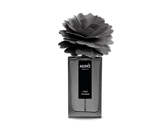 Profumatore per ambiente in una raffinata bottiglia in vetro colorato con etichetta effetto soft-touch con scritte dorate e diffusore a forma di fiore in legno di betulla naturale realizzato a mano. Completo di essenza da 100 ml. fragranza LEGNI ORIENTALI Fresche note di cedro... In negozio e online su tuttochic.live