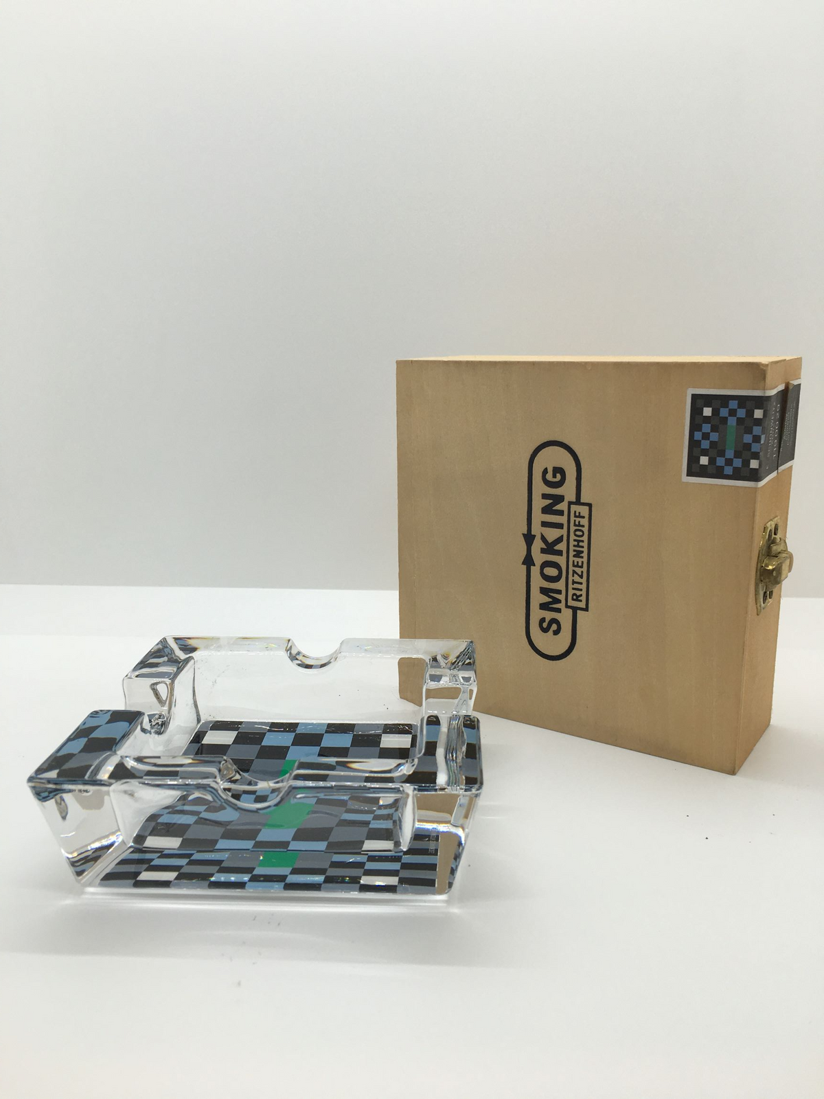 Posacenere quadrato in cristallo con decoro progettato da E. Schonweitz nel 2002, Edizione Limitata, della linea "Smoking" di Ritzenhoff. Custodito in una scatola di legno con cerniere e chiusura in metallo Dimensioni: mm. 100 x 100