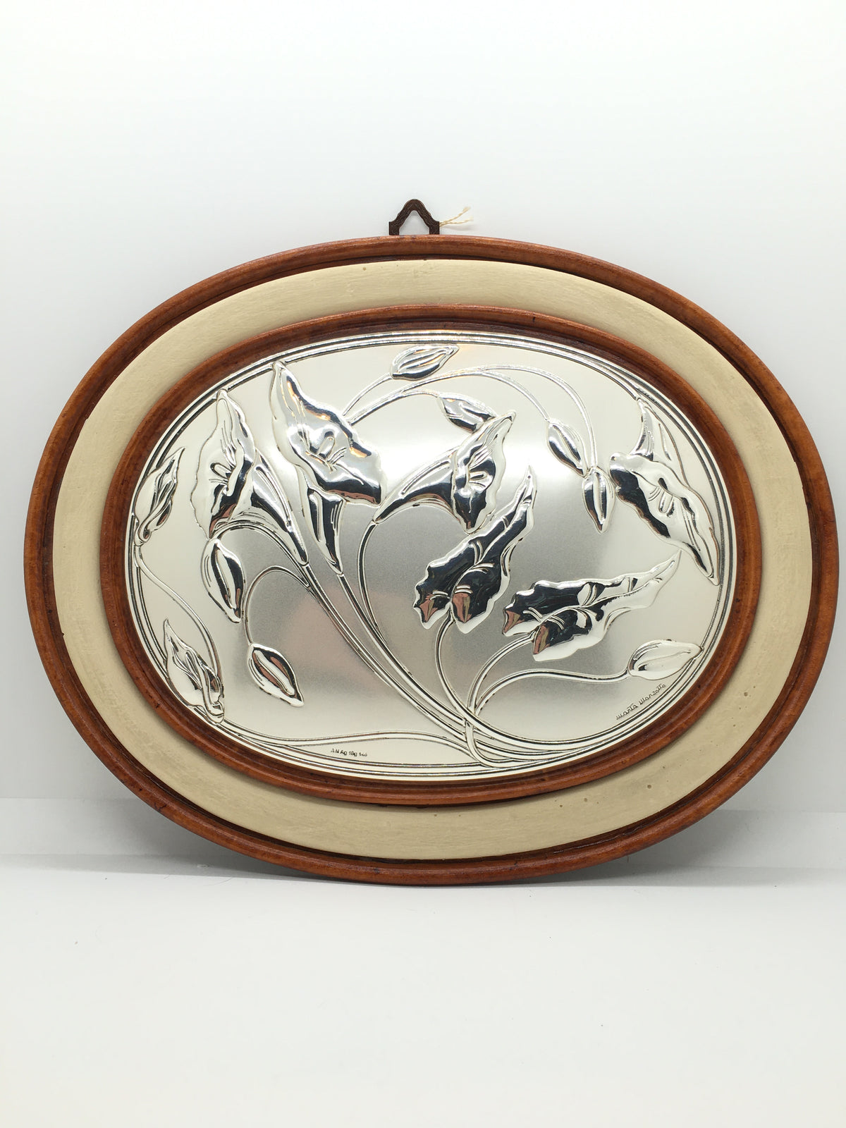 Quadretto ovale con cornice in ceramica effetto legno con decoro in argento laminato bombato raffigurante fiori e foglie di Calle. Disegnato da Marta Marzotto. Dimensioni: cm 31 x 25. In negozio e online su tuttochic.live