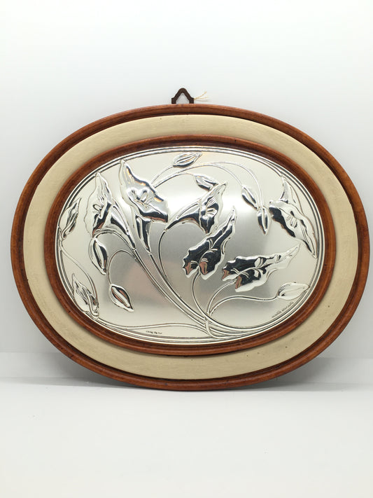 Quadretto ovale con cornice in ceramica effetto legno con decoro in argento laminato bombato raffigurante fiori e foglie di Calle. Disegnato da Marta Marzotto. Dimensioni: cm 31 x 25. In negozio e online su tuttochic.live